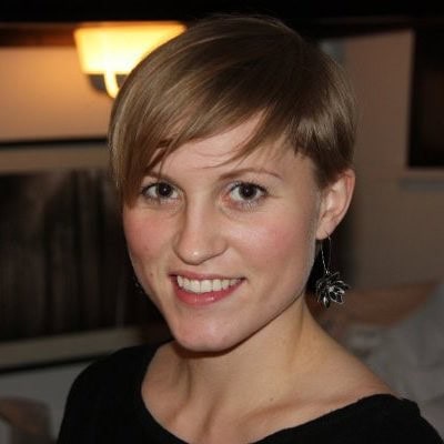 Portrait of Dr. Elin Hestmann Vinjerui smiling indoors with short blonde hair and floral earrings.