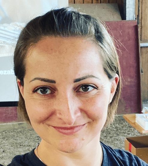 Dr. Caroline Rezabek smiling indoors with presentation equipment in the background.
