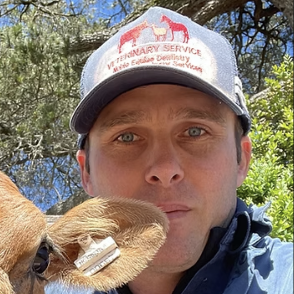 Nathan Noble wearing a veterinary service cap, posing with a tagged calf in an outdoor rural setting.